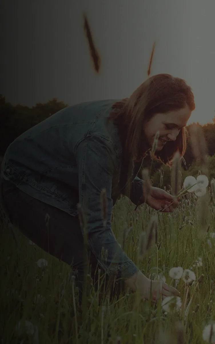 A woman picking dandelions in a field