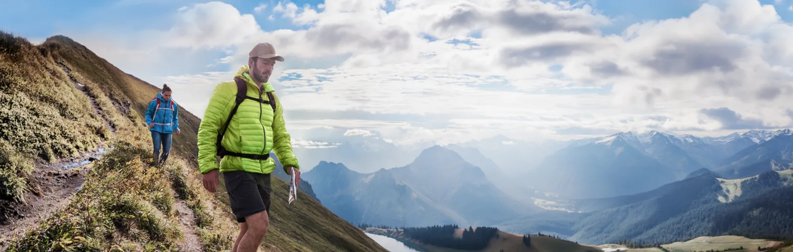 Two hikers trekking downward on a mountain trail with backpacks and a map, with purple gradient and arrow pointing down.